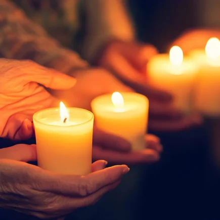 Diverse group holding candles during solemn candlelight vigil at night