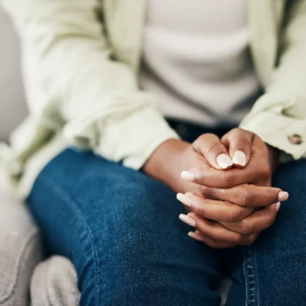 Anxiety, hands and woman on a sofa with stress