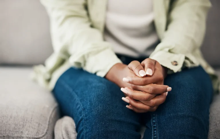 Anxiety, hands and woman on a sofa with stress