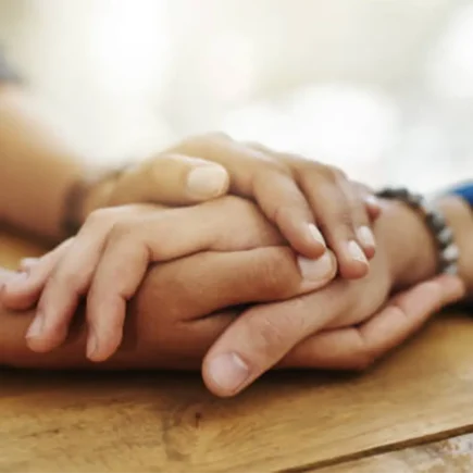 Holding each other hands for comfort and sympathy on table