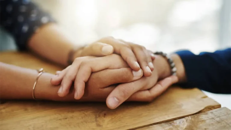 Holding each other hands for comfort and sympathy on table