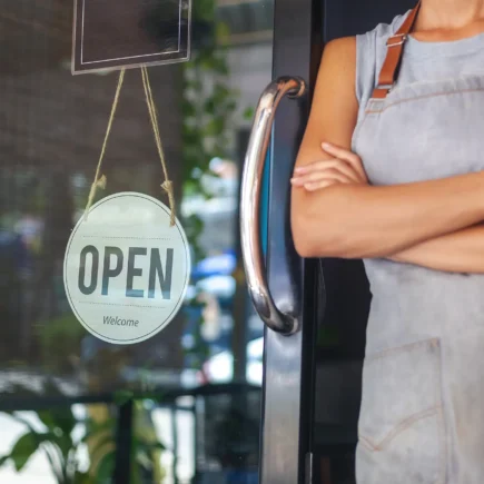 The woman is a waitress in an apron, the owner of the cafe stands at the door with a sign Open waiting for customers