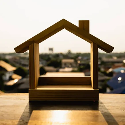 Wood House Model displayed on a table, with a vibrant city skyline in the background