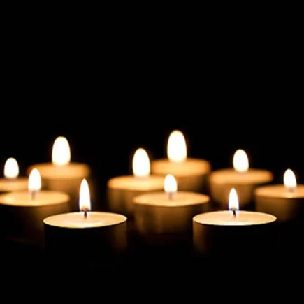 A collection of candles burns gently in the dark